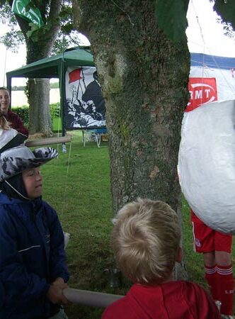 Kids hitting the alarm clock piñata.